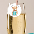 Load image into Gallery viewer, Champagne flute with a baby shower label featuring a teddy bear and gift box on a beige background.
