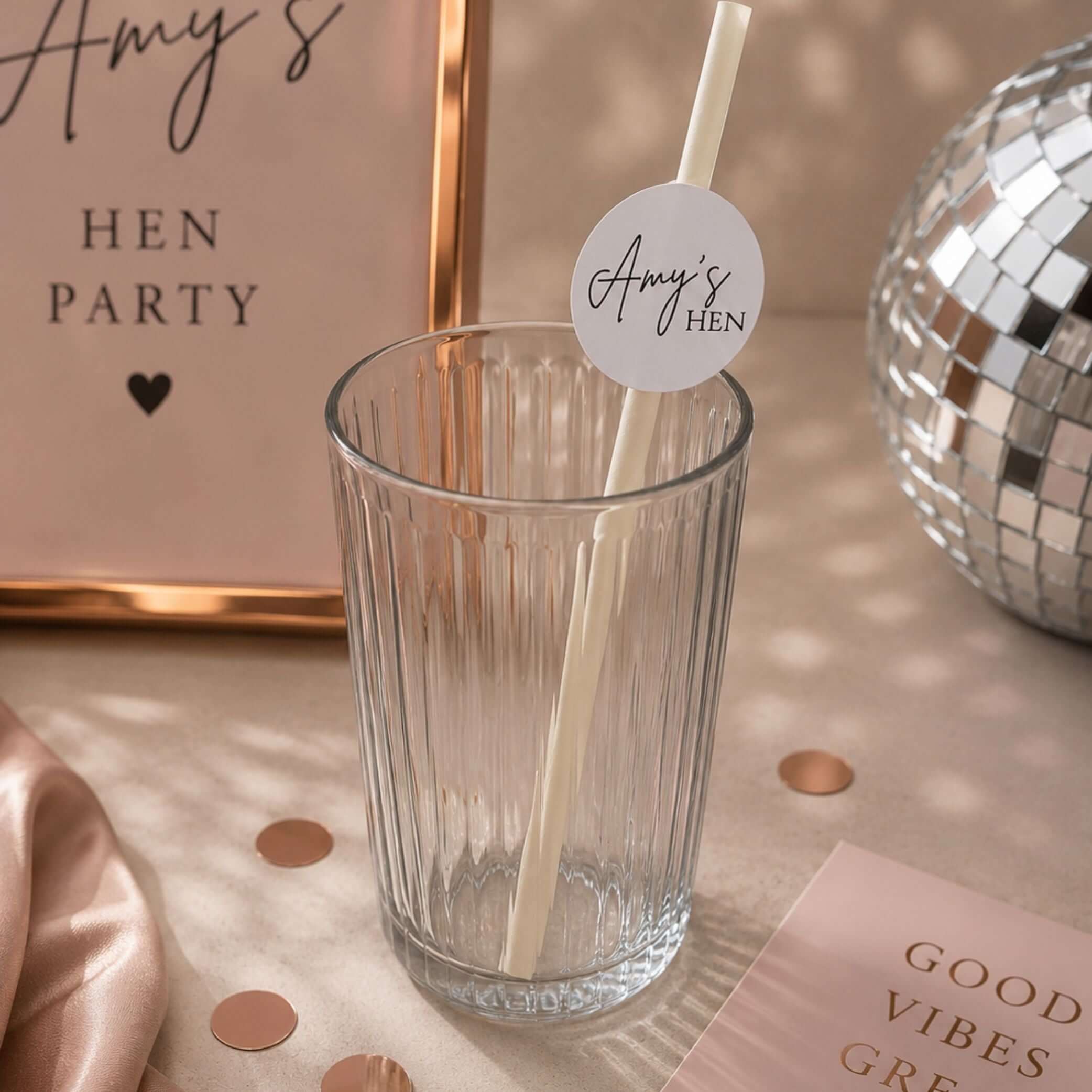 Hen party paper straws personalised toppers in a glass with decorative label for hen celebrations.