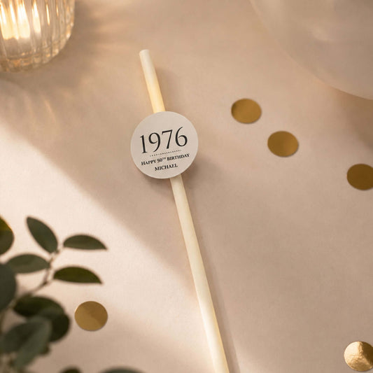 Personalised birthday year straw toppers featuring 1976 and Happy 50th Birthday Michael on a stylish table setting.