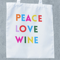 Load image into Gallery viewer, White tote bag featuring colorful text: PEACE LOVE WINE, perfect for wine lovers and trips to the winery.
