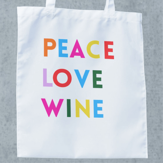White tote bag featuring colorful text: PEACE LOVE WINE, perfect for wine lovers and trips to the winery.