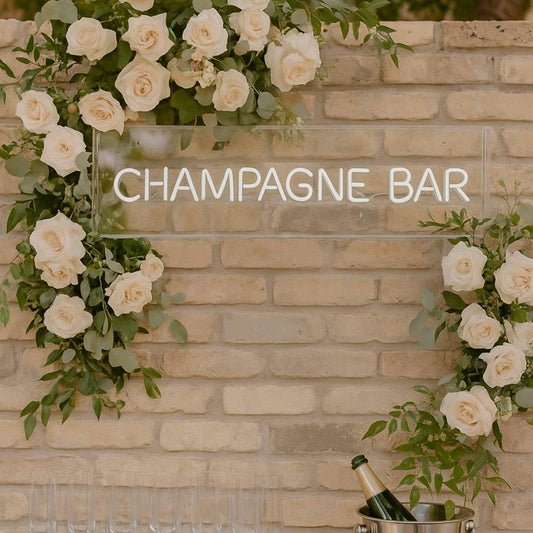 Champagne bar neon sign pre-order displayed among white roses at an elegant event.