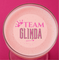 Load image into Gallery viewer, Pink cocktail topped with Team Glinda edible drink topper for a Wicked themed party.
