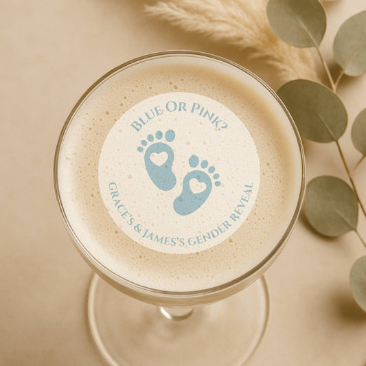 Glass of frothy beverage with a gender reveal cocktail topper with blue feet