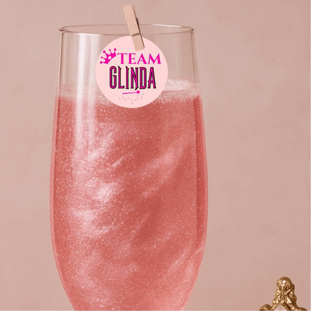 Pink drink with 'Team Glinda' edible topper for themed cocktails and party decorations.