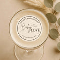 Load image into Gallery viewer, Glass with a 'Baby Love' label for a baby shower on a beige background with eucalyptus leaves.

