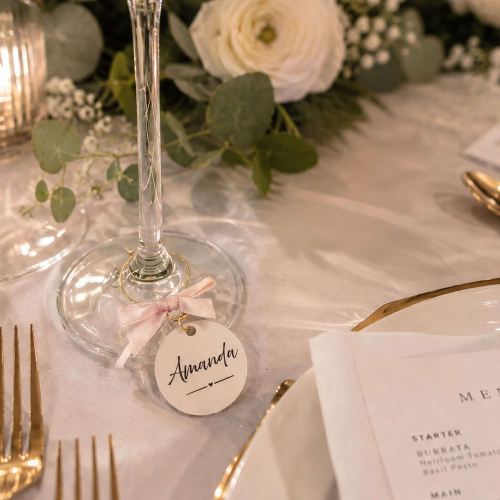 Personalised name wine glass charms with a tag labeled Amanda at a beautifully set table.