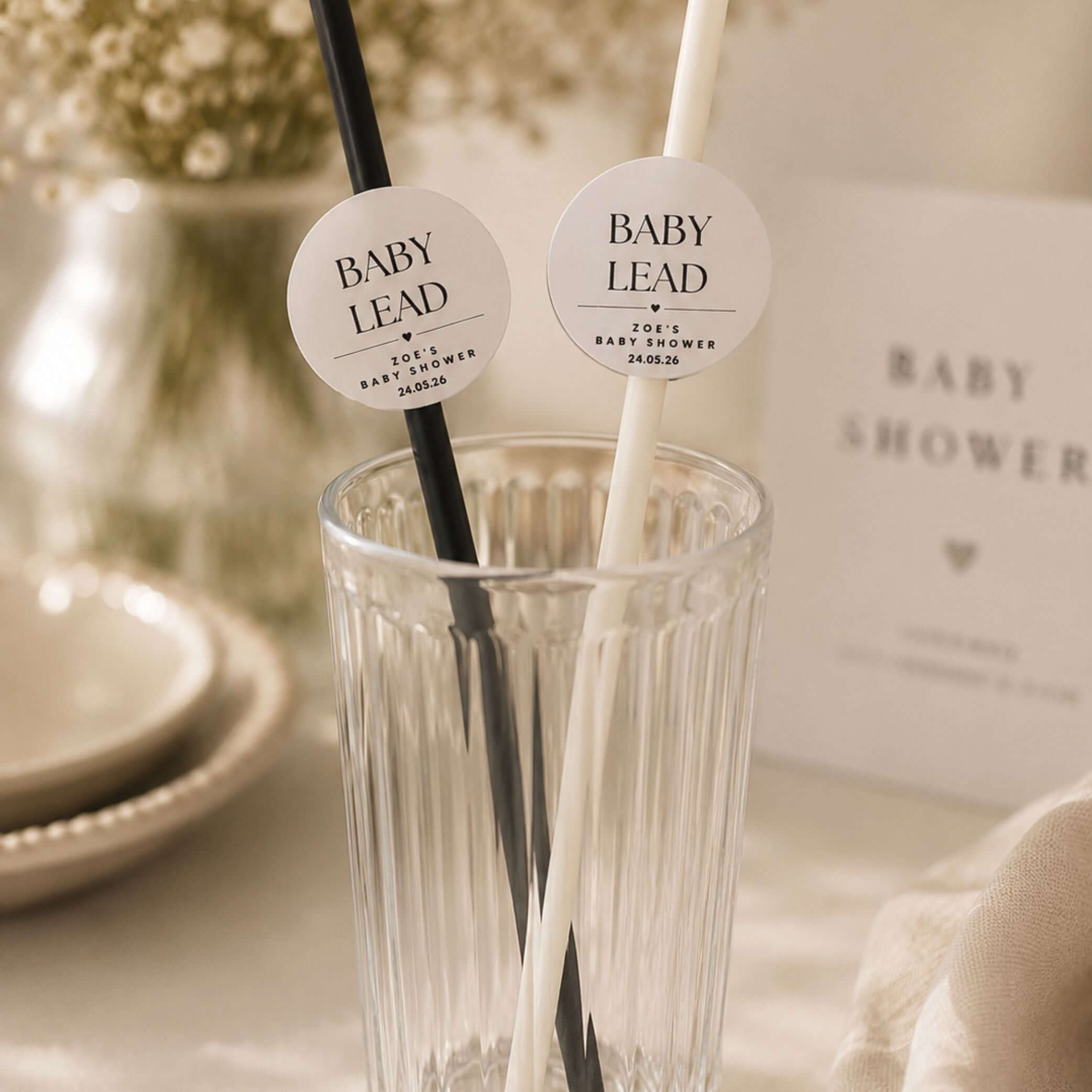 Personalised baby name paper straw toppers in black and white colors in a glass for baby shower celebrations.