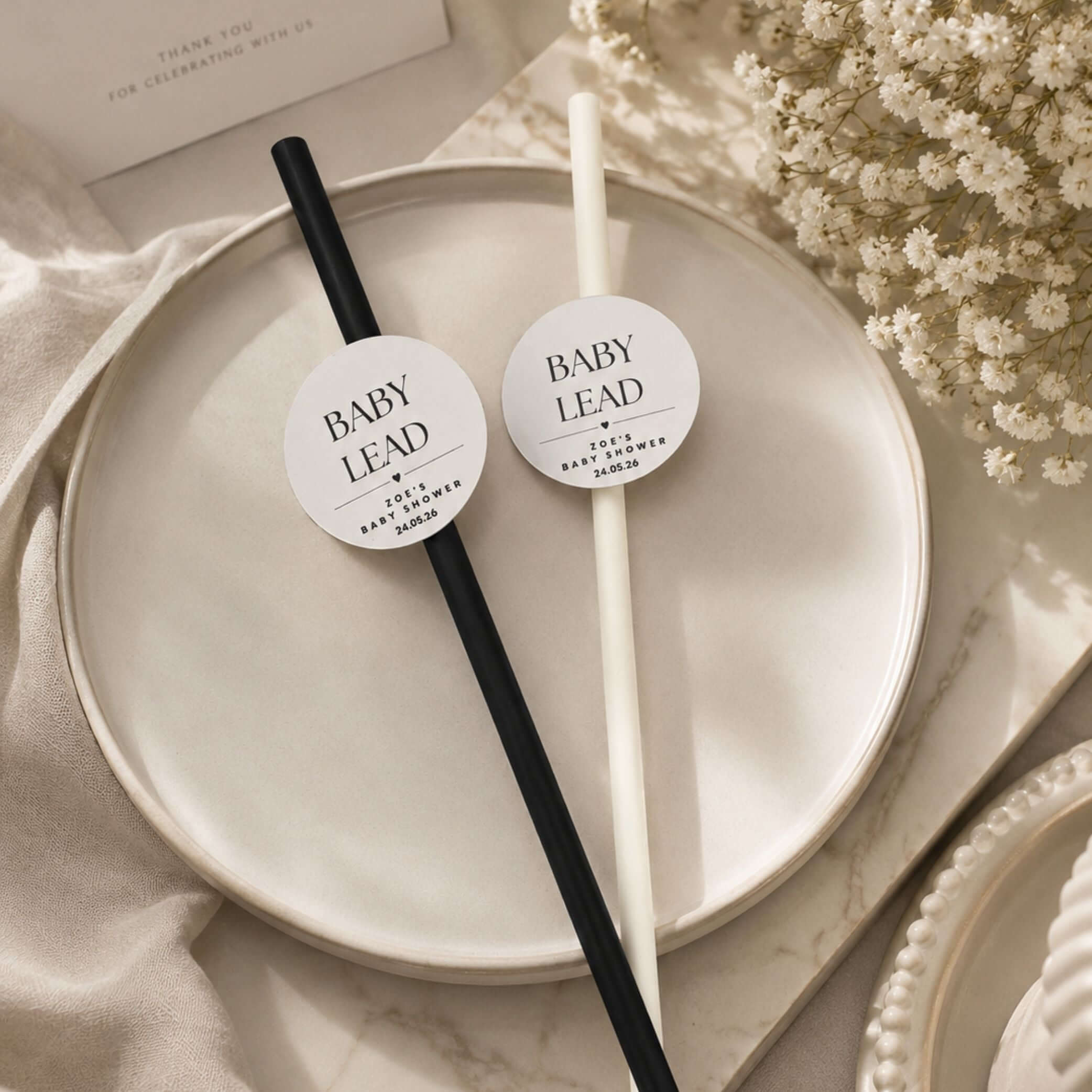 Personalised baby name paper straw toppers on a decorative plate, perfect for baby shower celebrations.