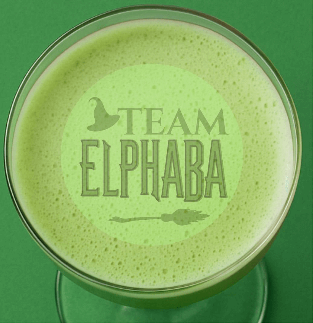 Green frothy drink with 'Team Elphaba' text, perfect for Wicked themed cocktails.