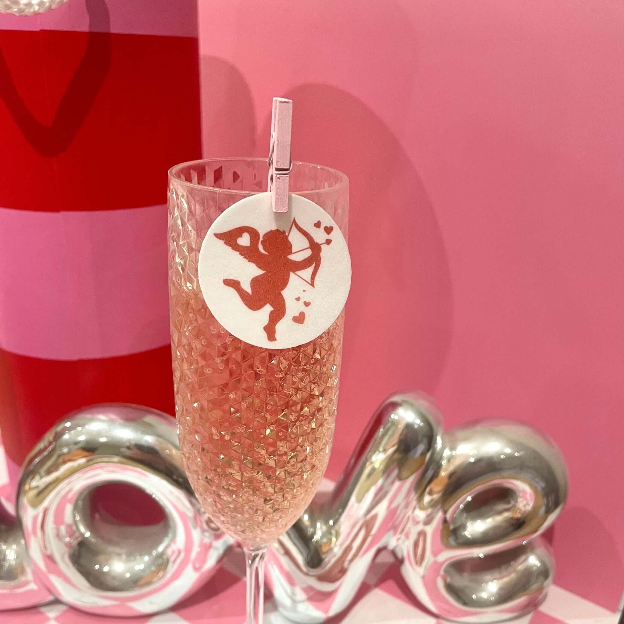 Valentine's drink toppers featuring a cute Cupid design on a champagne flute for stylish Valentine's cocktails.