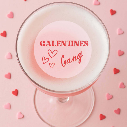 Edible drink toppers for cocktails featuring 'Galentines Gang' on a pink cocktail surrounded by heart-shaped sprinkles.