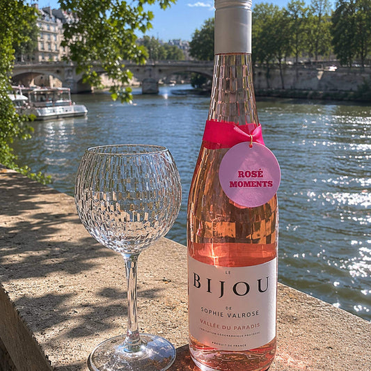 Rose Moments Bottle Charm Gift Tag on a bottle of rosé wine by the river with a crystal glass.